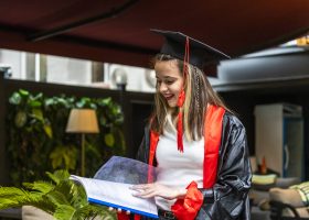 Young student wearing graduation cape and looking at to her notebook Young student wearing graduation cape and looking at to her notebook. High quality photo
